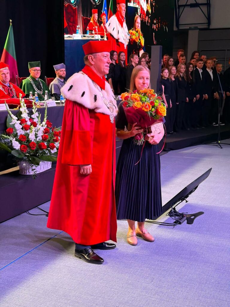 Zdjęcie Rektora w todze i Marii Bajak z kwiatami i statuetką za wygranie plebiscytu